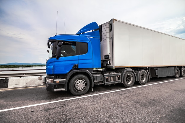 Blue truck on a road with refrigerator trailer