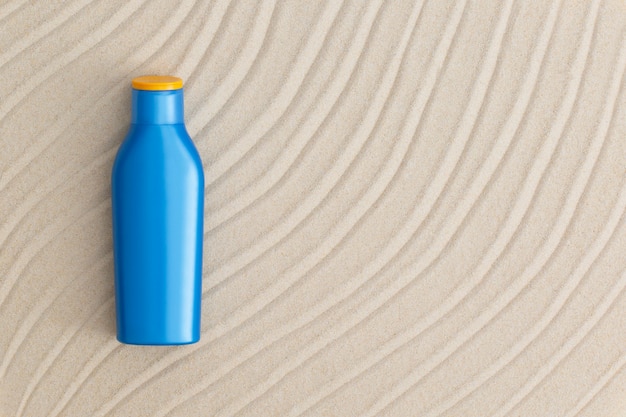 Blue tube of sunscreen on beach sand