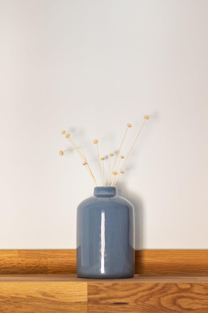 A blue vase with flowers in it and a white background.