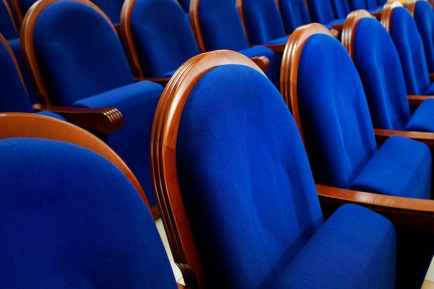 Blue velour chairs with armrests in the assembly hall expensive\
and noble furniture in a row closeup