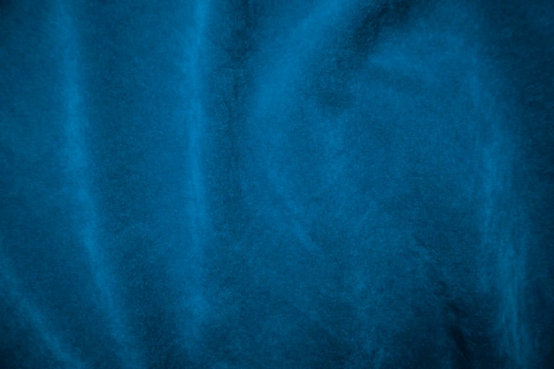 背景として使用される青いベルベット生地のテクスチャです。柔らかく滑らかな繊維素材の青い生地の背景にテキスト用のスペースがあります。