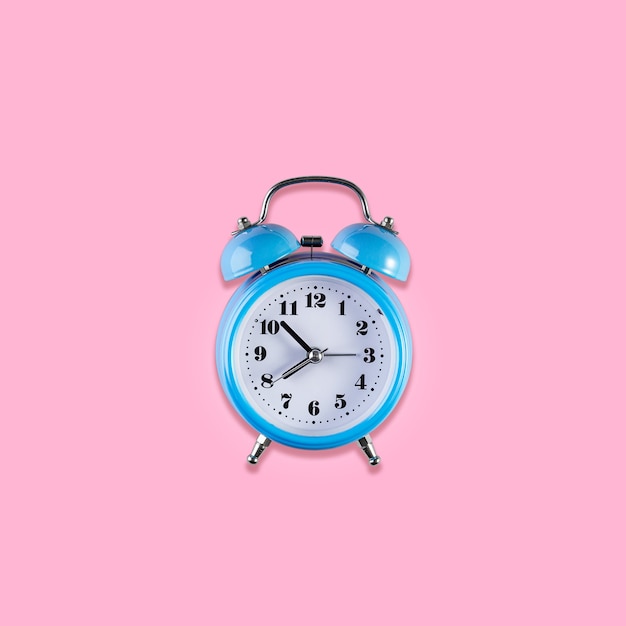 淡いピンク色の背景に青いヴィンテージ目覚まし時計。テキストの場所と目覚まし時計。時間管理の概念、事業計画。上面図。正方形の画像。