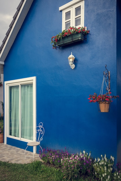 Blue wall with light green curtain. Window is decorated with flower,