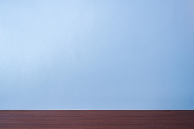 A blue wall with a wooden floor and a wooden table in front of it.