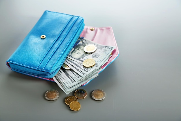 Blue wallet with dollar bills on the grey background