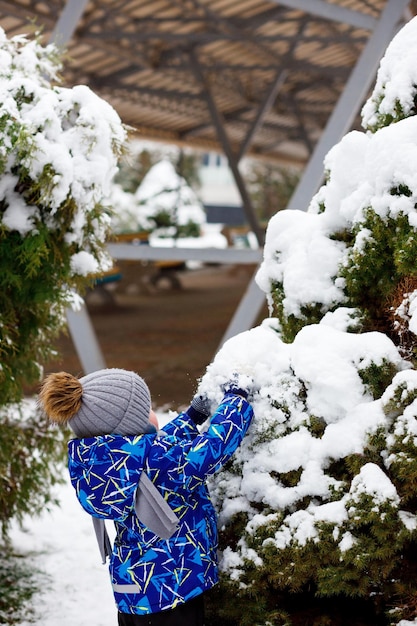 Blue warm children's jacket A lot of snow in November Children's games near Christmas trees