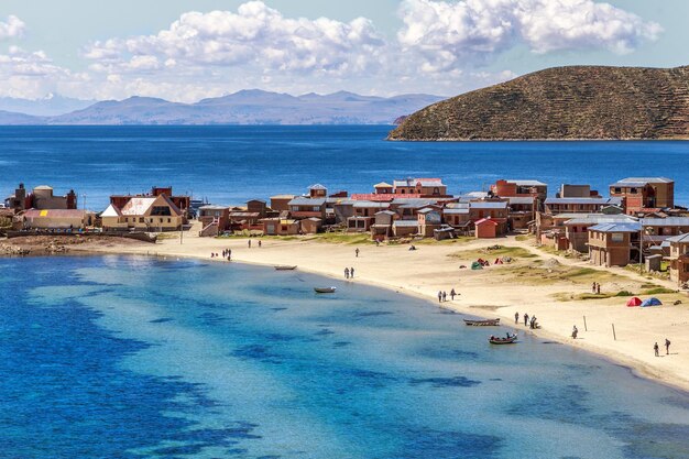 Blue water and coast of titicaca lake boats walking people and bolivian village at incas island of the sun bolivia south america