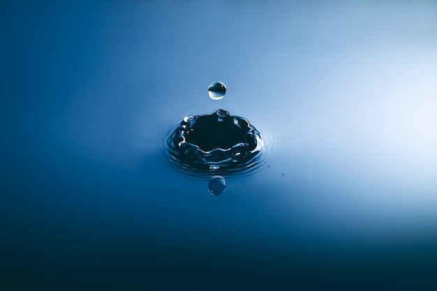 Photo blue water drop falling down and circles wave.