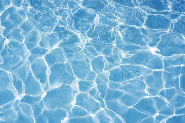 Blue water surface with bright sun light reflections, water in swimming pool background