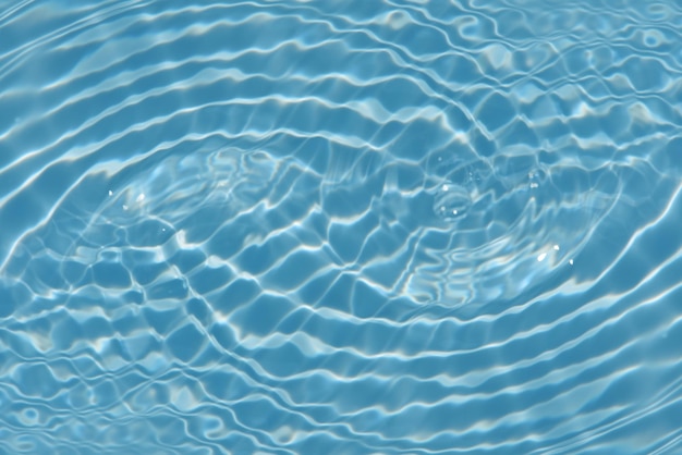 Blue water in a swimming pool with ripples and the sun reflecting on the surface