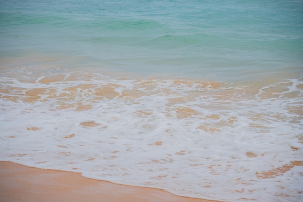 Blue waves of the ocean and yellow sand of the beach.