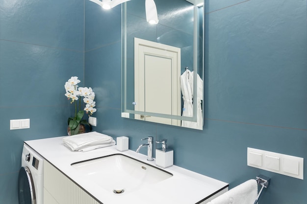 Blue and white bathroom with big mirror towels lighting and countertop basin