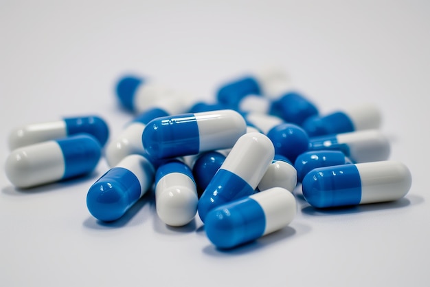 Blue and White Capsules Scattered on a Clean White Surface Close Up Detail