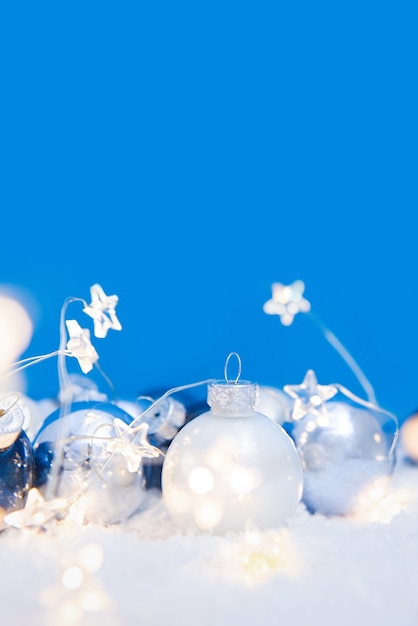 Blue and White Christmas balls with illuminated garland on snow