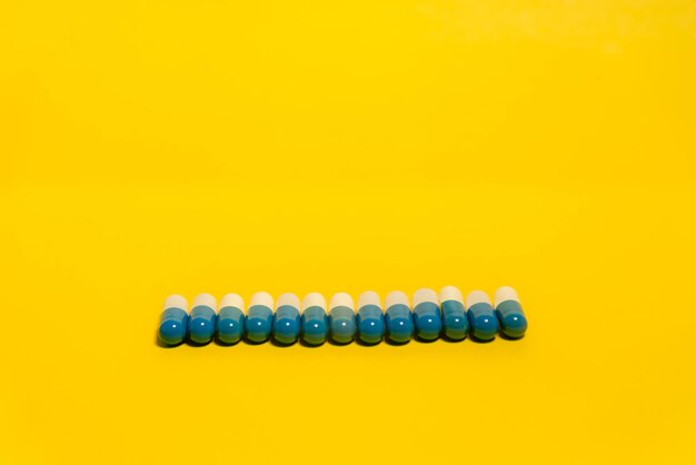 Blue and white colored pills in a row on a blue surface medical supplies