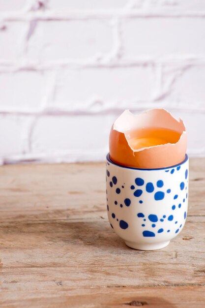A blue and white egg sits in a cup on a wooden table