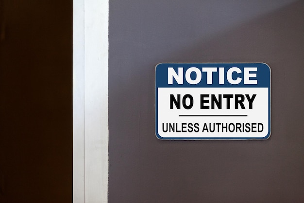 Photo blue and white notice sign on the side of an open door stating notice no entry unless authorised