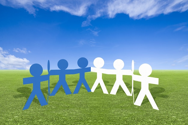 Blue and white people paper holding hands standing on the\
meadow. world population day concept