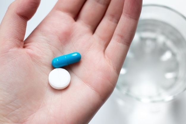 Photo blue and white pill capsule on the female palm. antidepressant pills in female hand.