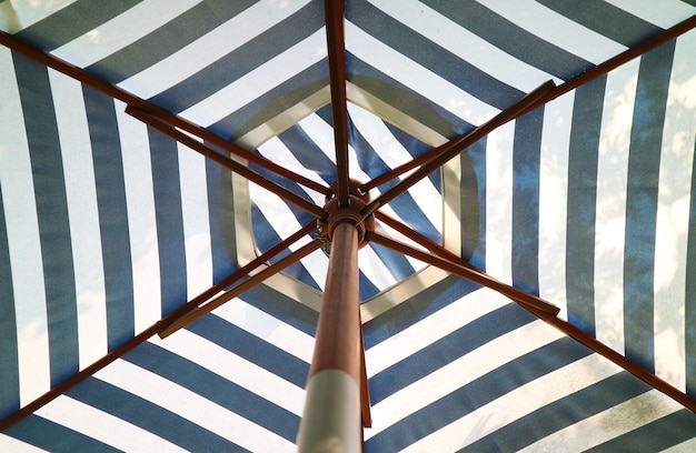 Blue and white striped beach umbrella in the sunlight