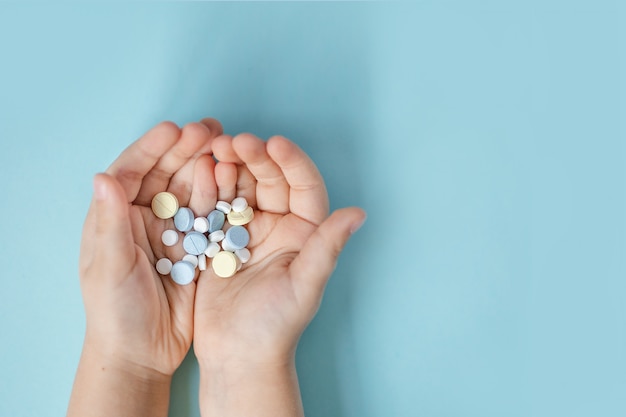 blue, white and yellow tablets in the palms on a blue background