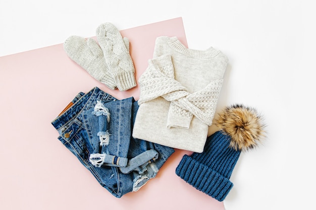 Blue winter hat with jeans, sweater and  mittens on white background. Women's stylish autumn or winter clothes. Trendy clothes collage. Flat lay, top view.