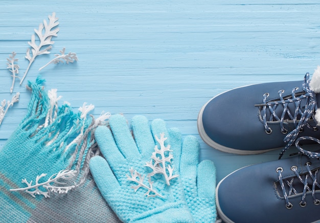 Blue winter shoes and gloves on blue wooden background