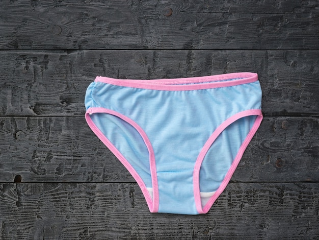 Blue women's panties with a red border on a black wooden table