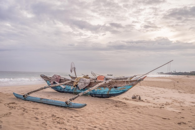 Blue wooden fishing boat on the sandy beach of the atlantic ocean at the cloudy day.