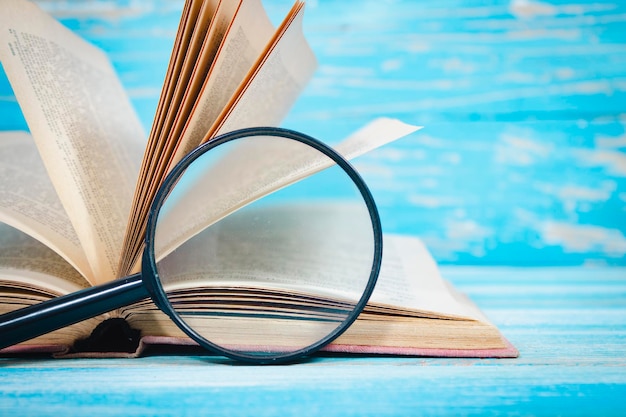 Foto su un tavolo di legno blu un libro e una lente d'ingrandimento