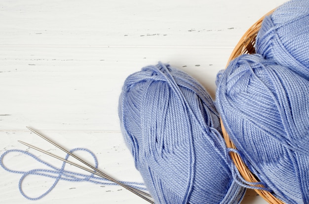 Blue yarn and knitting needles in a round wicker basket