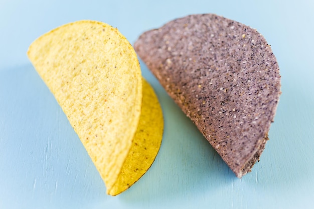 Blue and yellow corn taco shells on a blue background.