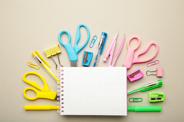 Blue, yellow, pink, green school supplies with notebook on grey background. Back to school concept.