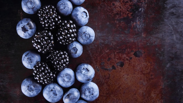 어두운 배경의 블루베리와 블랙베리 녹슨 배경 복사 공간에 모듬된 열매