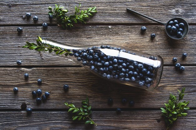 Blueberries in a bottle on wooden background