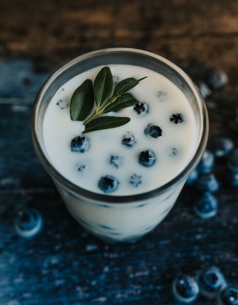 Blueberries float in a transparent glass with milk