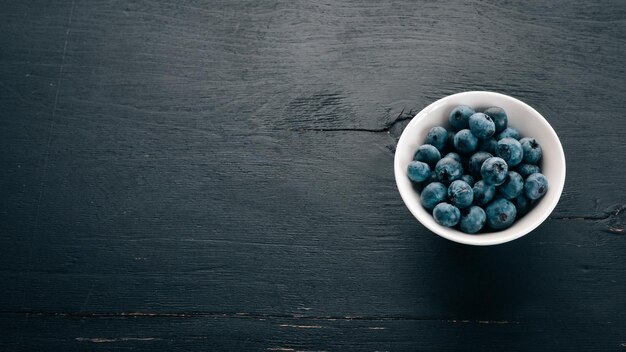 Blueberries Fresh berries in the plateOn the black wooden background Free space for text