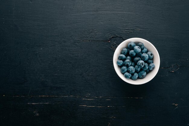 Blueberries Fresh berries in the plateOn the black wooden background Free space for text