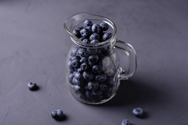 Blueberries in a glass jug on a gray concrete background The benefits of berries vegetarianism concept