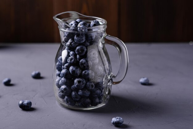 Blueberries in a glass jug on a gray concrete background The benefits of berries vegetarianism concept