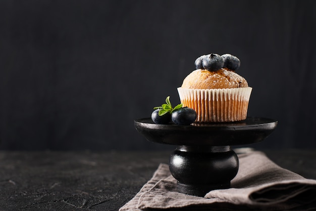 Muffin ai mirtilli o cupcakes con foglie di menta su struttura nera