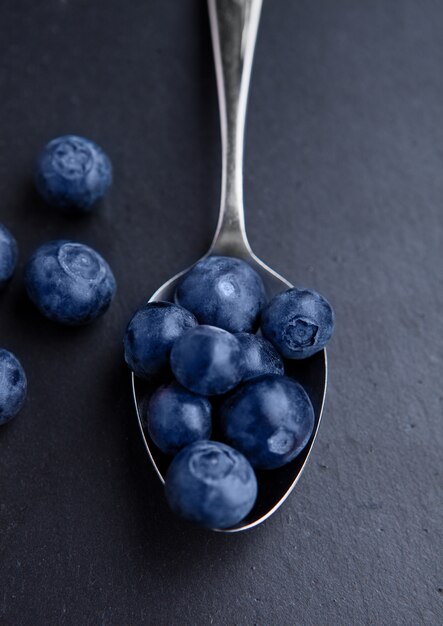 Blueberries on old spoon on black stone kitchen board