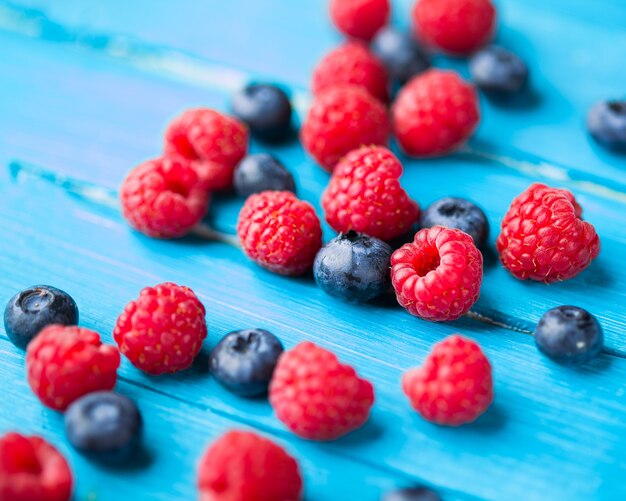 Blueberries and raspberries on blue wooden table