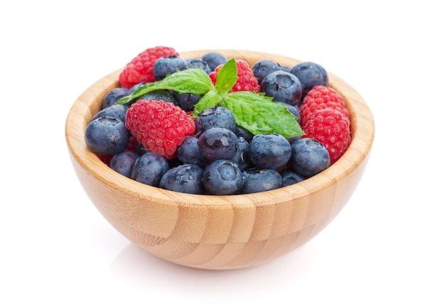 Blueberries and raspberries with mint leaf. Isolated on white background