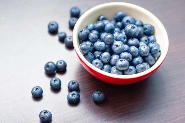 Blueberries in a red bowl on wooden table