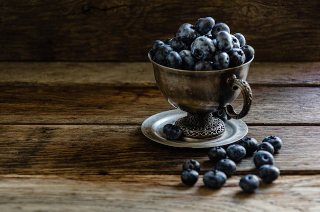 Blueberries in a silver cup, on a wooden table. Ripe berries in the kitchen, harvest.