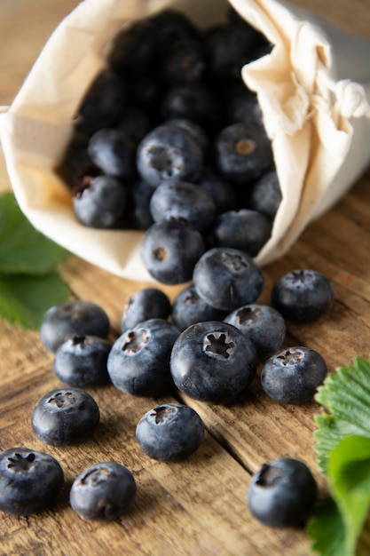 Blueberries spilling out of a eco bag over rustic wood table. Zero waist concept.