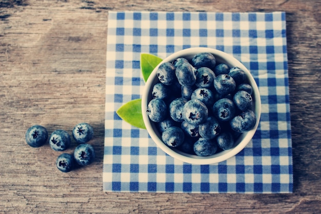 Blueberries in a white bowl on a wooden table