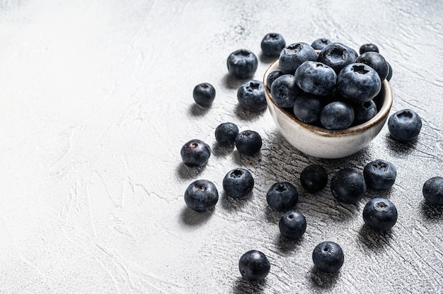 Blueberries in a white ceramic bowl. Gray background. Top view. Copy space.