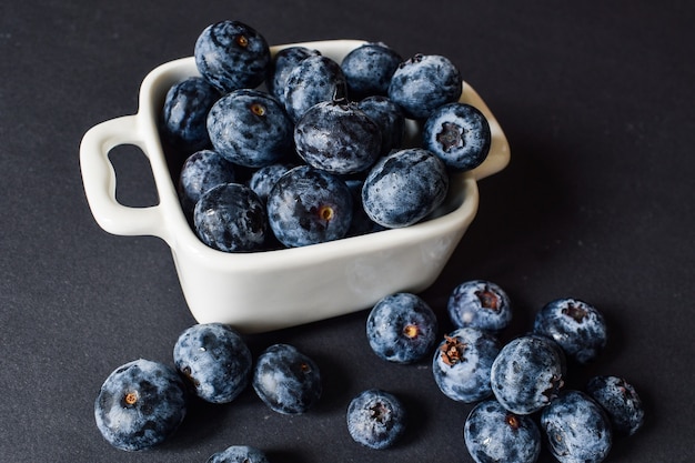 Blueberries in a white cup on a black surface